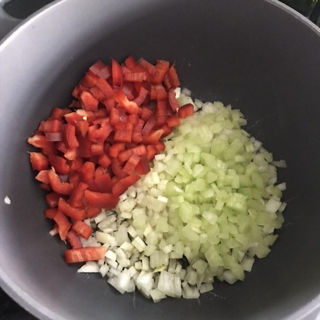 Coupez l'oignon, le céleri et le poivron en petit dés. Faites les revenir avec de l'huile d'olive pendant 5 minutes. Mélangez régulièrement pour assurer une cuisson régulière et pour que les légumes ne brûlent pas.