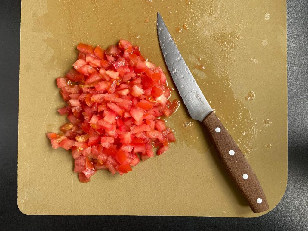 tomate hachée en dés sur une planche à découper